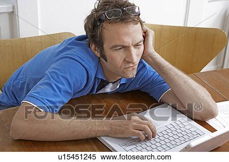 Stock Photography - Bored Mid Adult Man Using Laptop. Fotosearch