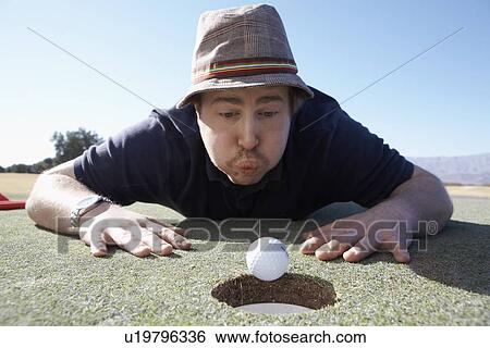 Man blowing golf ball to hole View Large Photo Image Stock Photograph - Man blowing golf ball to hole. Fotosearch