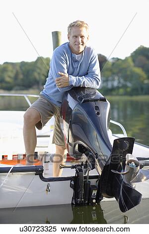 Stock Photography - Man leaning on outboard motor (portrait). Fotosearch