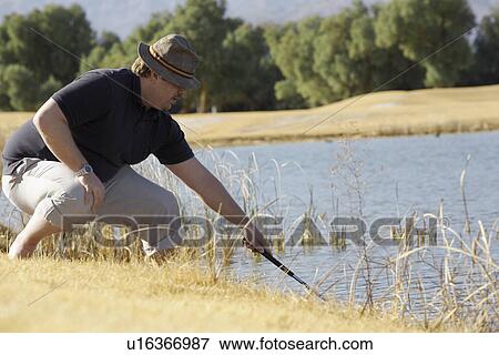 Man looking for golf ball in pond View Large Photo Image Stock Photo - Man looking for golf ball in pond. Fotosearch