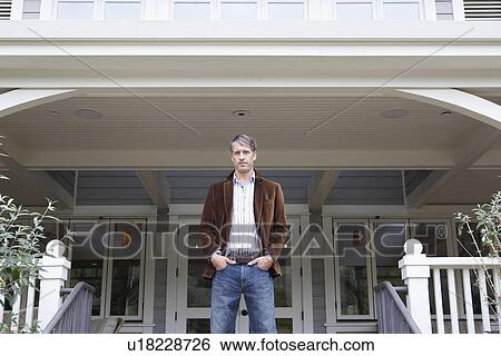 Stock Photograph - Man standing outside house (portrait, low angle view). Fotosearch