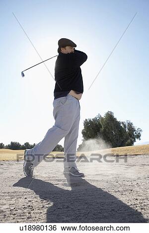 Stock Photograph - Man swinging golf club. Fotosearch