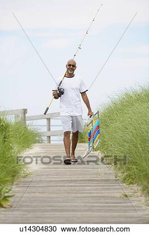 Man with fishing rod and folding chair walking on boardwalk View Large Photo Image Stock Image - Man with fishing rod and folding chair walking on boardwalk. Fotosearch