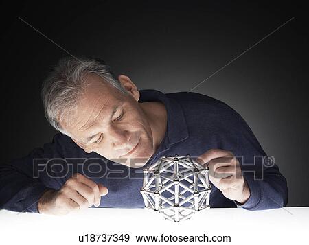 Stock Photo - Mature man examining puzzle. Fotosearch