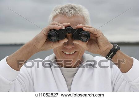 Stock Photo - Mature man looking through binoculars. Fotosearch