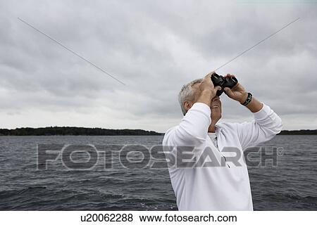 Mature man looking through binoculars View Large Photo Image Stock Photo - Mature man looking through binoculars. Fotosearch