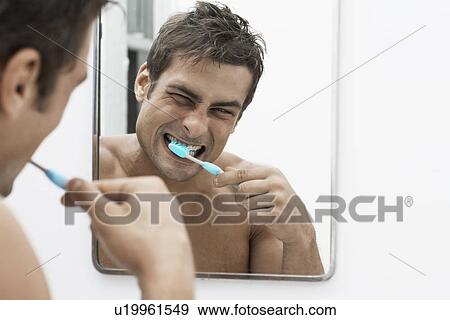 Stock Photo - Mid adult man cleaning teeth. Fotosearch