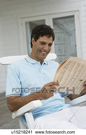 Mid adult man reading newspaper on lounge chair View Large Photo Image Stock Image - Mid adult man reading newspaper on lounge chair. Fotosearch