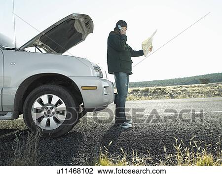 Mid adult man with road map talking on cell phone by broken car, low angle view View Large Photo Image Stock Image - Mid adult man with road map talking on cell phone by broken car, low angle view. Fotosearch
