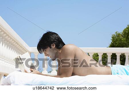 Young man reading book on balcony View Large Photo Image Stock Image - Young man reading book on balcony. Fotosearch