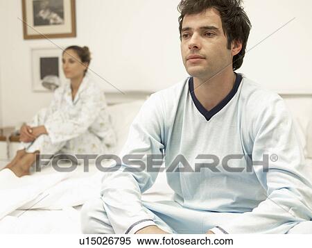 Stock Photography - Arguing young couple sitting on bed. Fotosearch