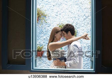 Couple hugging by window View Large Photo Image Stock Photo - Couple hugging by window. Fotosearch
