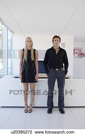 Stock Image - Couple standing in living room. Fotosearch