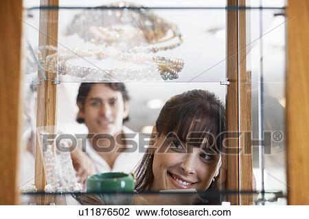 Woman shopping jewelry, boyfriend in background View Large Photo Image Stock Image - Woman shopping jewelry, boyfriend in background. Fotosearch