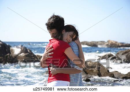 Stock Image - Young couple hugging by sea. Fotosearch