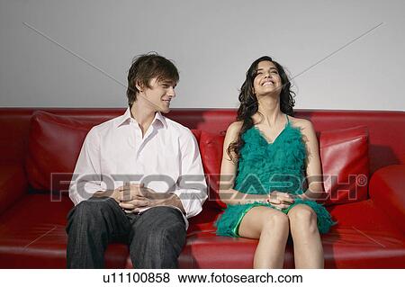 Stock Photo - Young couple laughing on sofa. Fotosearch
