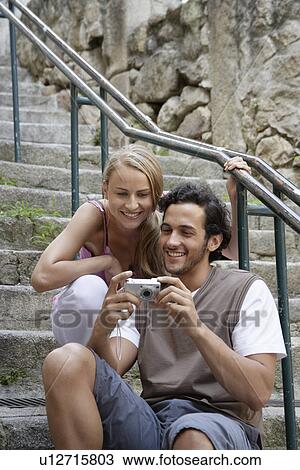Young couple looking at digital camera View Large Photo Image Stock Image - Young couple looking at digital camera. Fotosearch