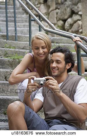 Stock Photograph - Young couple looking at digital camera. Fotosearch