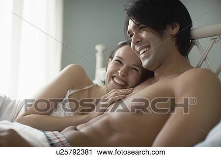 Young couple lying on bed View Large Photo Image Stock Image - Young couple lying on bed. Fotosearch