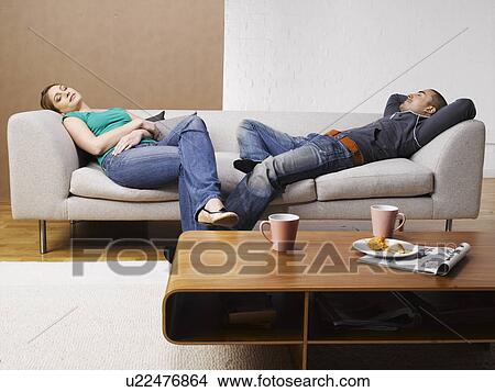 Young couple relaxing on sofa View Large Photo Image Picture - Young couple relaxing on sofa. Fotosearch