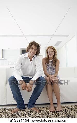 Young couple sitting on sofa View Large Photo Image Picture - Young couple sitting on sofa. Fotosearch