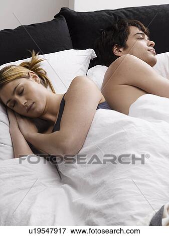Stock Photo - Young couple sleeping on bed. Fotosearch