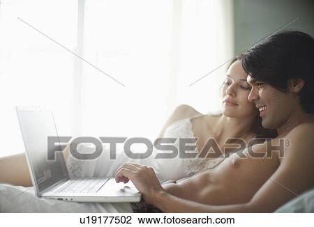 Young couple using laptop computer on bed View Large Photo Image Stock Image - Young couple using laptop computer on bed. Fotosearch