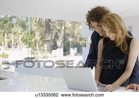 Young couple using laptop on kitchen counter View Large Photo Image Stock Image - Young couple using laptop on kitchen counter. Fotosearch