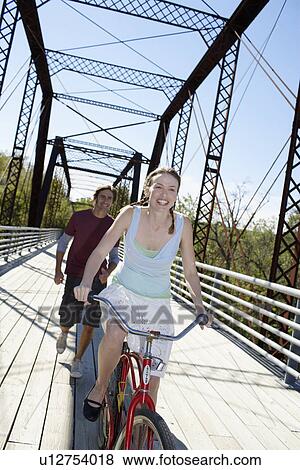Young woman cycling and man running on bridge View Large Photo Image Stock Photo - Young woman cycling and man running on bridge. Fotosearch