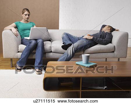 Young woman using laptop on sofa, boyfriend sleeping next to her View Large Photo Image Stock Photography - Young woman using laptop on sofa, boyfriend sleeping next to her. Fotosearch