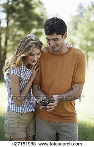 Stock Photo - Young couple holding pine cones. Fotosearch