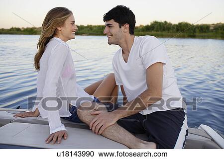 Stock Image - Young couple on motorboat at lake. Fotosearch