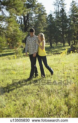Stock Image - Young couple walking in a field of wildflowers. Fotosearch
