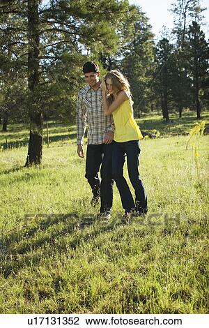 Stock Image - Young couple walking in a field of wildflowers. Fotosearch