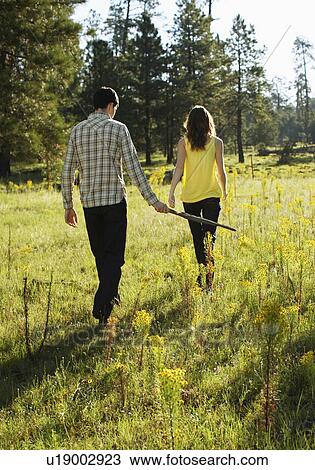 Young couple walking in a field of wildflowers View Large Photo Image Stock Image - Young couple walking in a field of wildflowers. Fotosearch