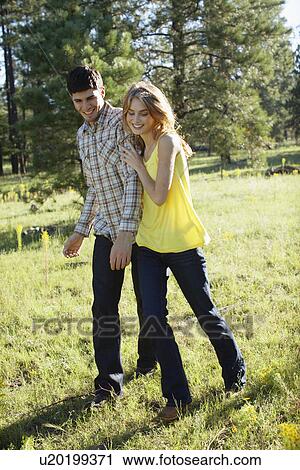 Stock Image - Young couple walking in a field of wildflowers. Fotosearch