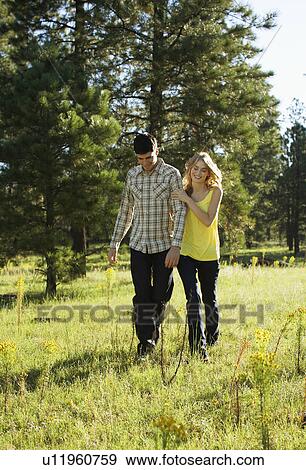 Young couple walking in a field of wildflowers View Large Photo Image Stock Photo - Young couple walking in a field of wildflowers. Fotosearch