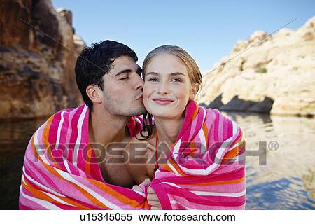 Young couple wrapped in a towel, man kissing woman on cheek View Large Photo Image Stock Photography - Young couple wrapped in a towel, man kissing woman on cheek. Fotosearch
