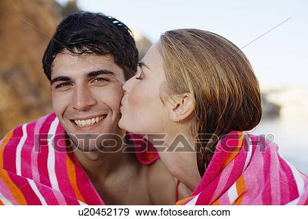 Young couple wrapped in a towel, woman kissing man on cheek View Large Photo Image Stock Photo - Young couple wrapped in a towel, woman kissing man on cheek. Fotosearch