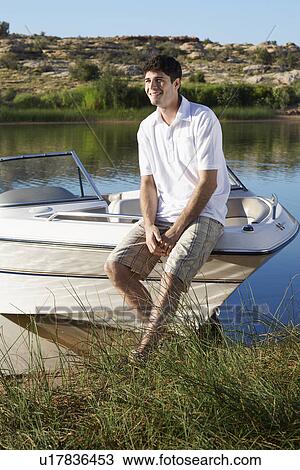 Young man sitting on motorboat View Large Photo Image Stock Image - Young man sitting on motorboat. Fotosearch