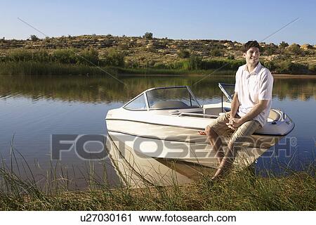 Young man sitting on motorboat View Large Photo Image Stock Image - Young man sitting on motorboat. Fotosearch