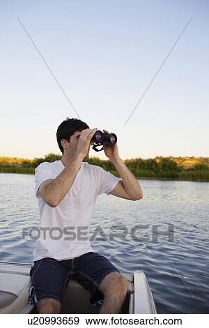 Young man using binoculars at lake View Large Photo Image Stock Photo - Young man using binoculars at lake. Fotosearch
