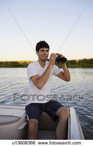 Young man using binoculars at lake View Large Photo Image Stock Photograph - Young man using binoculars at lake. Fotosearch
