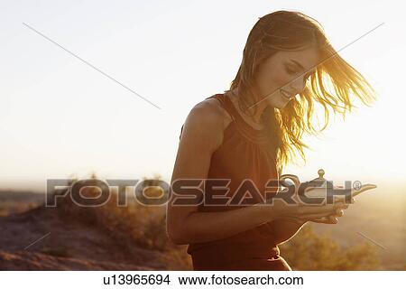 Picture - Young woman holding genie lamp. Fotosearch