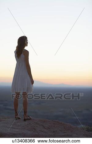 Stock Photograph - Young woman looking at view at sunset. Fotosearch