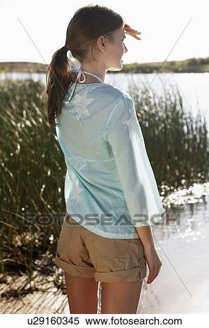 Young woman shielding eyes and looking at lake View Large Photo Image Stock Photography - Young woman shielding eyes and looking at lake. Fotosearch