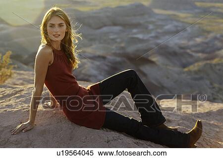 Stock Photography - Young woman sitting on rock. Fotosearch