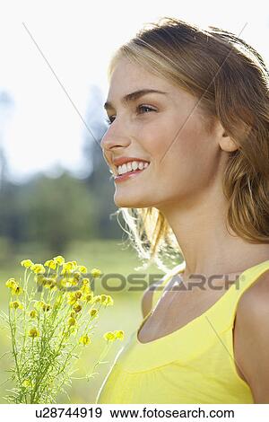 Young woman with a wildflower View Large Photo Image Stock Photo - Young woman with a wildflower. Fotosearch