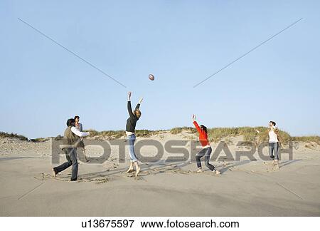 Stock Photo - Five people playing with ball on beach. Fotosearch