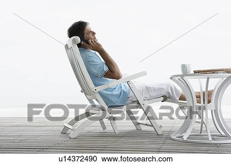 Stock Image - Mid adult man on phone near beach. Fotosearch